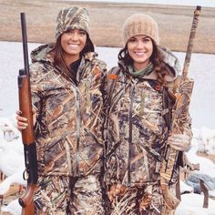 two women in hunting gear holding shotguns