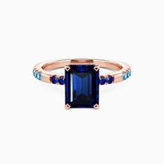 a ring with an emerald and blue sapphire stones on the side, set in rose gold