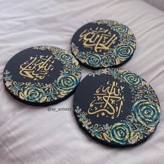 three black and gold coasters with arabic calligraphy on the front one has blue roses