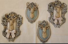 three deer head mounted to the side of a wall in an ornately decorated frame