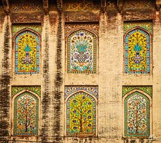 an old building with colorful stained glass windows on the front and side wall, decorated with flowers and leaves