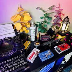 an old fashioned typewriter sitting on top of a desk next to some flowers and books