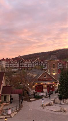 the town is surrounded by mountains and buildings at dusk, with pink clouds in the sky