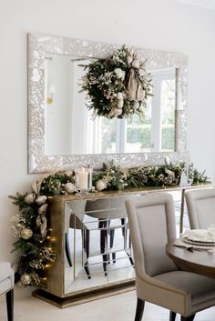 a dining room table decorated for christmas with greenery and candles on the sideboard