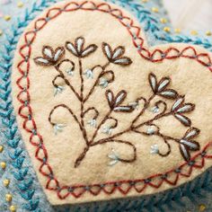 a heart shaped pillow with embroidered flowers on it