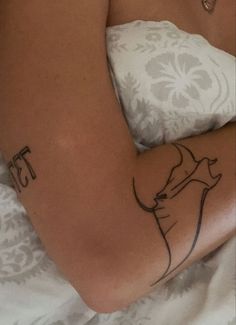 a woman laying in bed with a tattoo on her arm and the word ests