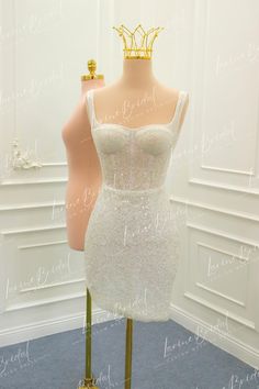 a mannequin wearing a white dress with a gold crown on top