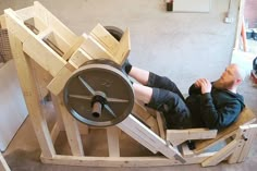 a man is sitting in a chair made out of wood and has a machine on it