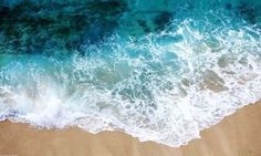 an aerial view of the ocean with waves coming in to shore and people walking on the beach