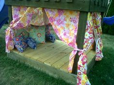 a bed made out of wood with flowers on the sheets and pillows, tied to it