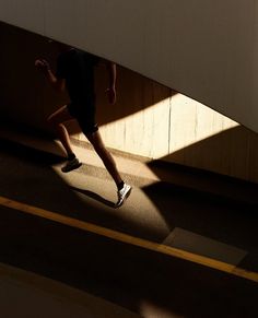 a person is running under an overpass in the sun with their shadow on the ground