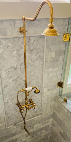 a gold shower faucet in the corner of a bathroom