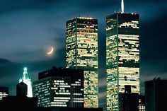 two skyscrapers lit up at night with the moon in the sky