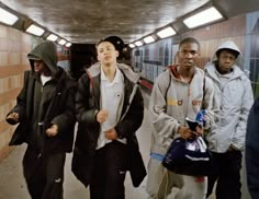 four young men are walking down the subway