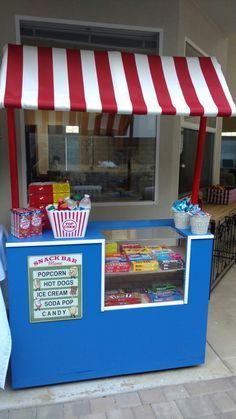 a blue and white food stand with red and white awning on it's side