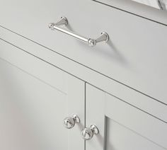 a white dresser with two handles and knobs