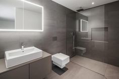 a bathroom with a sink, toilet and shower stall in the background is illuminated by neon lights