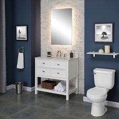 a white toilet sitting next to a sink in a bathroom under a mirror and lights