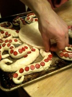 a person is decorating some cookies with white icing and red circles on them