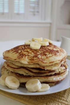 a stack of pancakes with banana slices and syrup