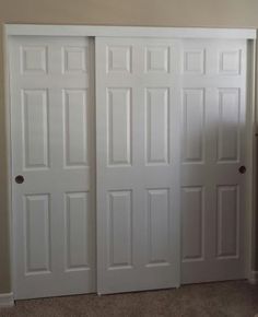 two white doors in a room with carpeting