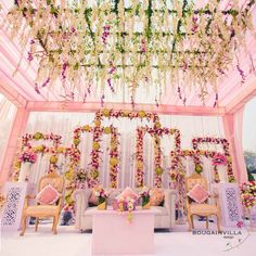 an outdoor wedding setup with flowers and greenery on the ceiling, couches and chairs