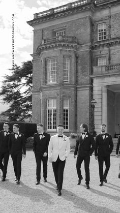 a group of men in tuxedos walking towards a building