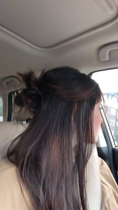 a woman sitting in the back seat of a car with long hair on her head