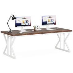 two computer monitors sitting on top of a wooden desk