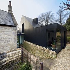 a black building with a glass door in front of it and stone walls around it