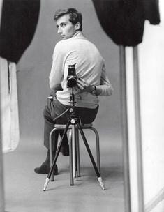 a man sitting on top of a chair holding a camera