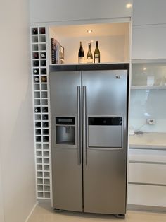 a silver refrigerator freezer sitting inside of a kitchen next to a wine bottle rack