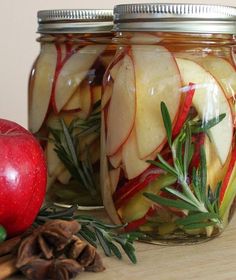 two jars filled with food sitting on top of a wooden table next to an apple