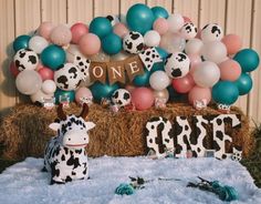 a birthday party with balloons, decorations and cow figurines on hay bales