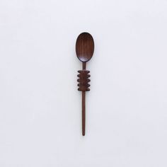 a wooden spoon sitting on top of a white wall next to a brown fork with two ends