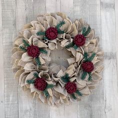 a wreath made out of burlocks with red flowers and green leaves on it