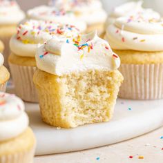 cupcakes with white frosting and sprinkles on a plate