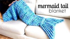 a woman laying on top of a white couch under a blue knitted mermaid tail blanket