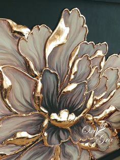 a close up of a metal object with flowers on it's sides and gold leafy petals