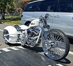 a white motorcycle parked next to a silver van