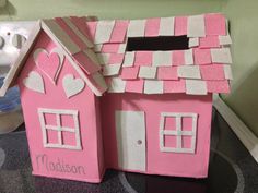 a pink doll house with hearts on the roof and windows, sitting on a counter