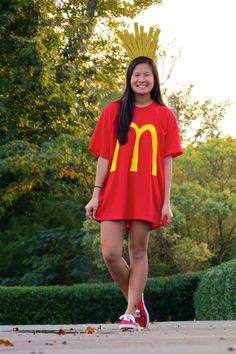 a woman in a mcdonald's shirt and crown walks down the street