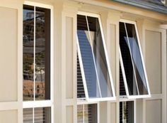 three windows with white shutters on the side of a house