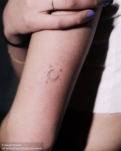 a woman's arm with a small crescent tattoo on the left side of her arm