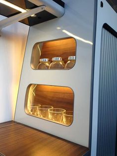 the inside of a small space with wooden shelves and glass containers on each shelf in front of it