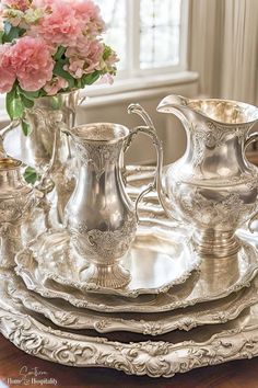 an ornate silver plate set with flowers in vases on the side and other items