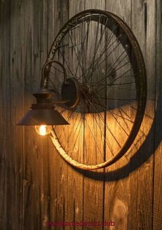 an old bicycle wheel mounted to the side of a wooden wall next to a lamp