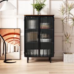 a black cabinet sitting on top of a hard wood floor next to a potted plant