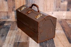 an old brown suitcase sitting on top of a wooden floor next to wood planks