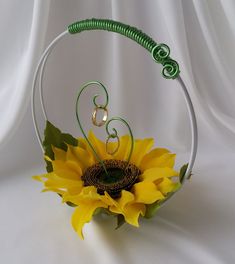 a sunflower in a wire basket on a white background with green spirals around it